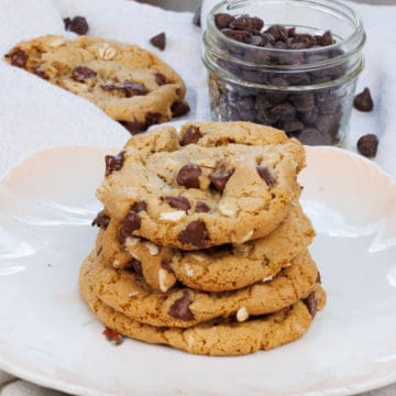 four oatmeal chocolate chip cookies on top of each other on a plate