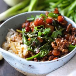 a blue bowl filled with spinach, tomatoes, and ground beef