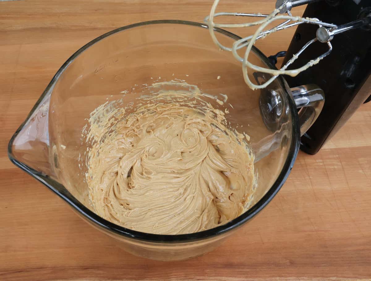 peanut butter and butter in a mixing bowl next to an electric mixer