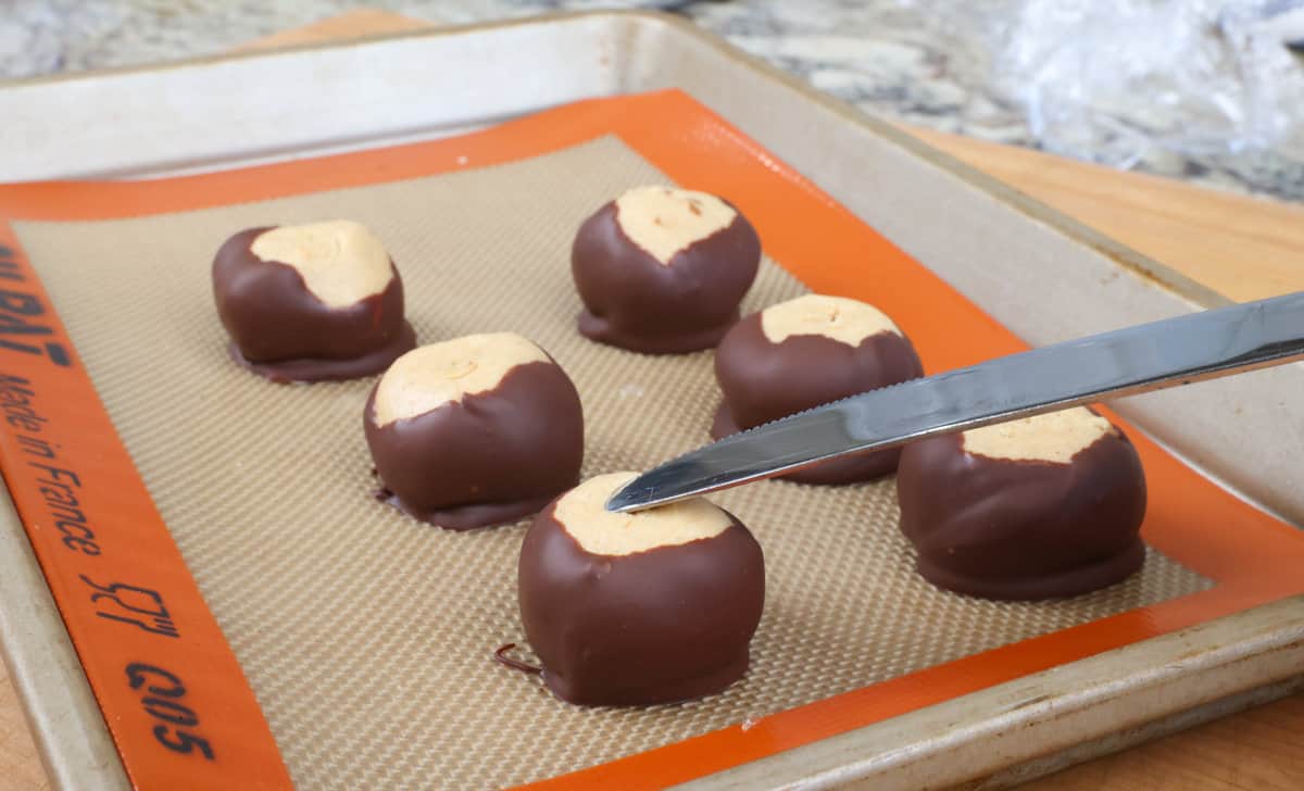 smoothing out the holes on top of buckeyes with a knife 