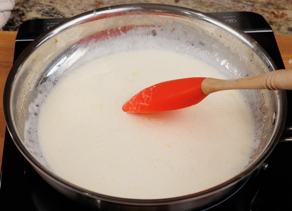 heavy cream and lemon juice simmering in a skillet on the stove