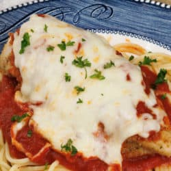 Chicken Parmesan topped with tomato sauce and melted mozzarella cheese on a blue plate