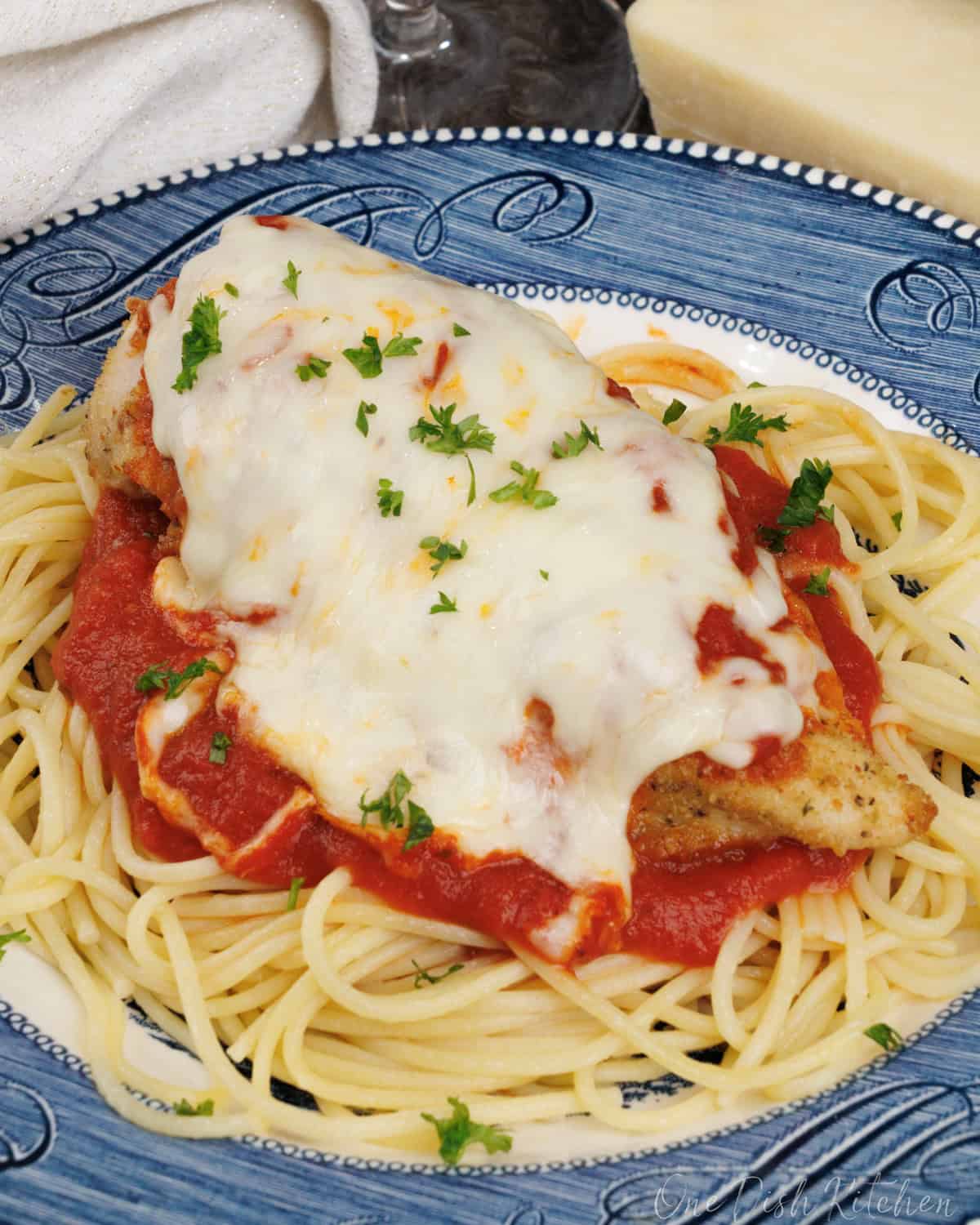 Chicken Parmesan topped with tomato sauce and melted mozzarella cheese on a blue plate.