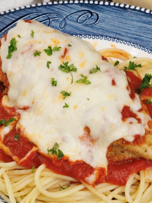 Chicken Parmesan topped with tomato sauce and melted mozzarella cheese on a blue plate.