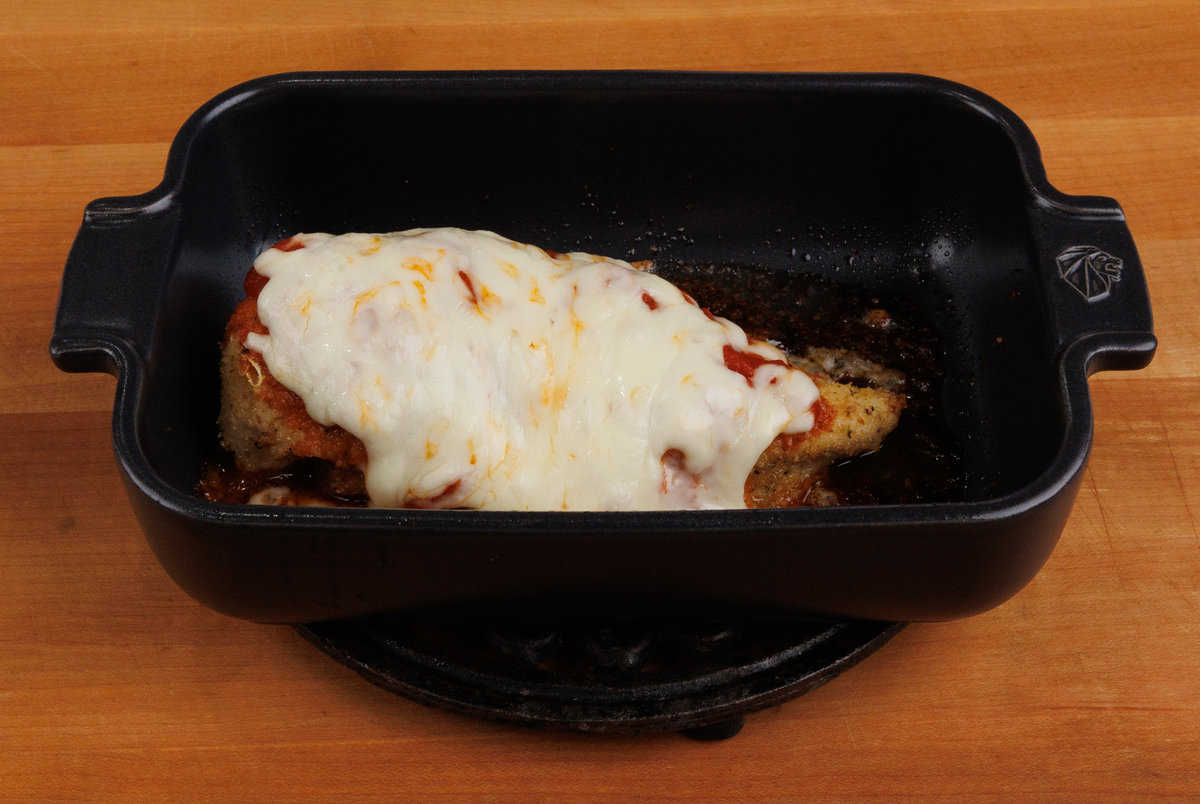 one chicken parmesan baked in a small dish resting on a kitchen counter