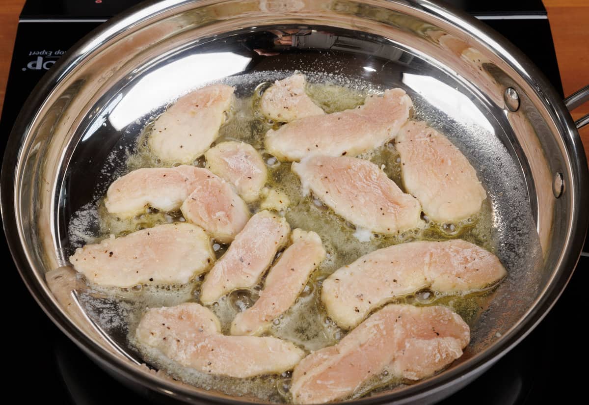 strips of chicken cooking in a skillet on the stove