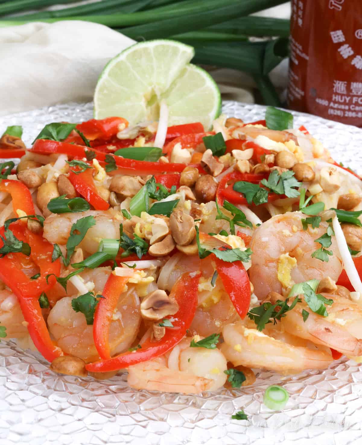 shrimp pad thai with peppers, bean sprouts and topped with chopped cilantro next to a white napkin