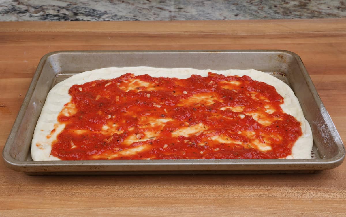 pizza sauce spread over an unbaked pizza crust.