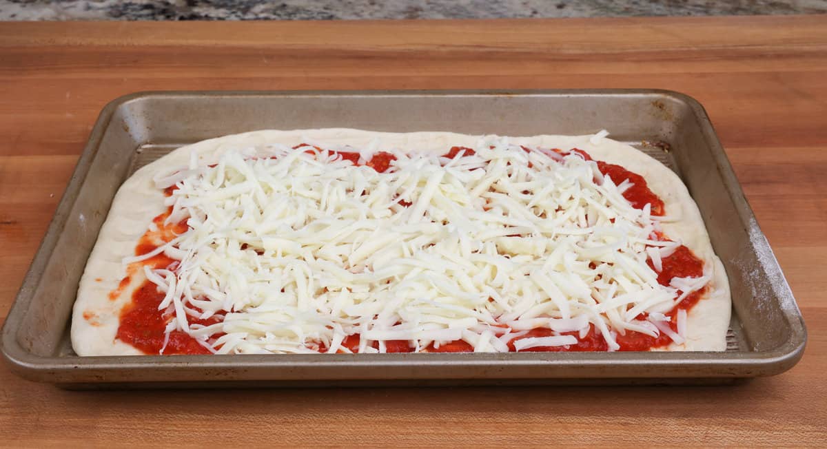 shredded mozzarella cheese sprinkled over the top of a pizza.