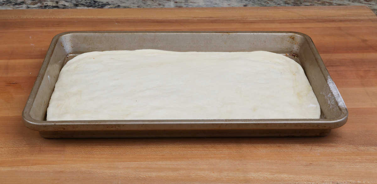 unbaked pizza dough on a small rectangular baking sheet