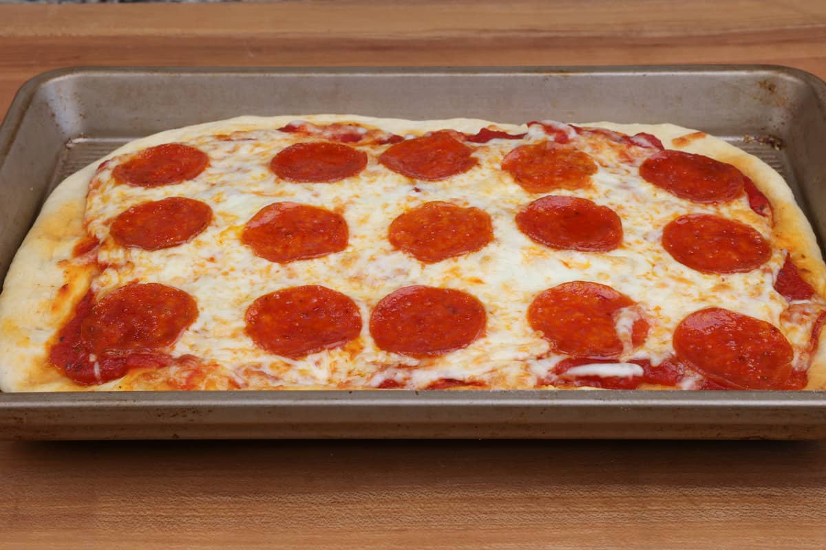a small pepperoni pizza on a rectangular baking sheet.