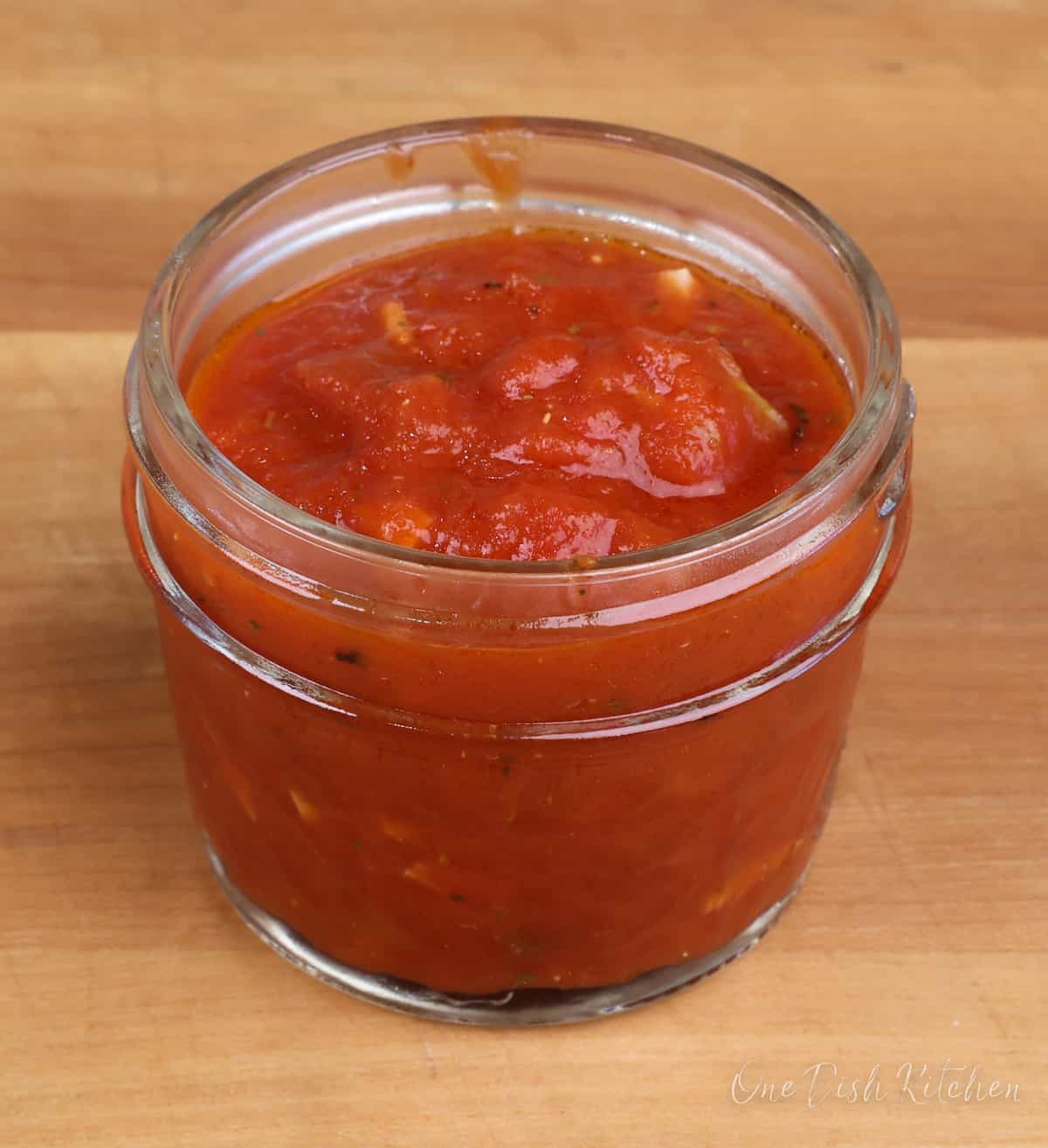 a small jar of homemade pizza sauce on a kitchen counter