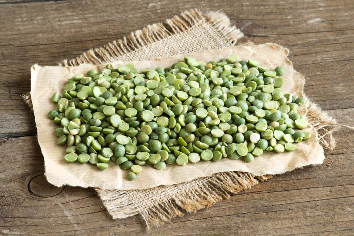 dried split peas on a piece of burlap on a wooden table.