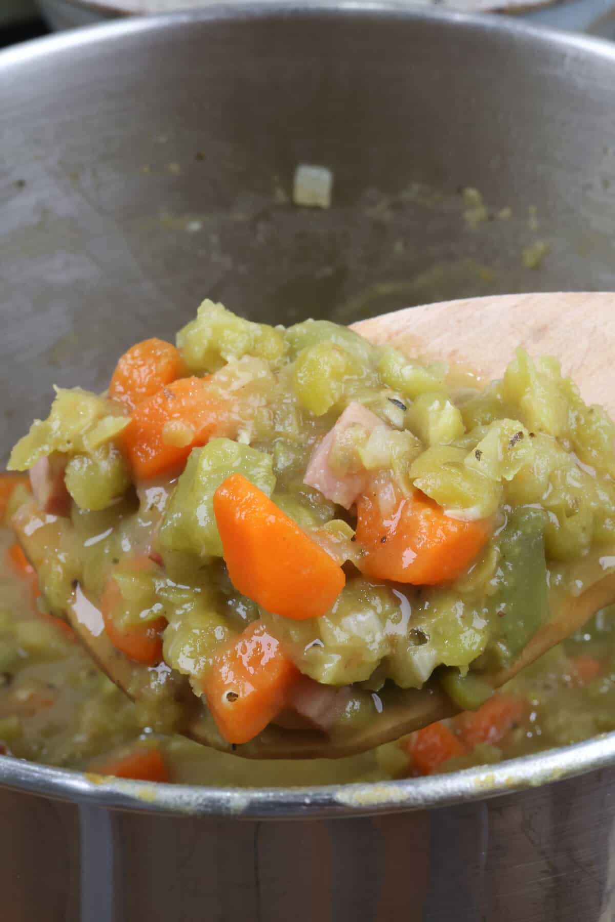 a small batch of split pea soup with ham in a pot with a wooden spoon resting on the edge of the pot