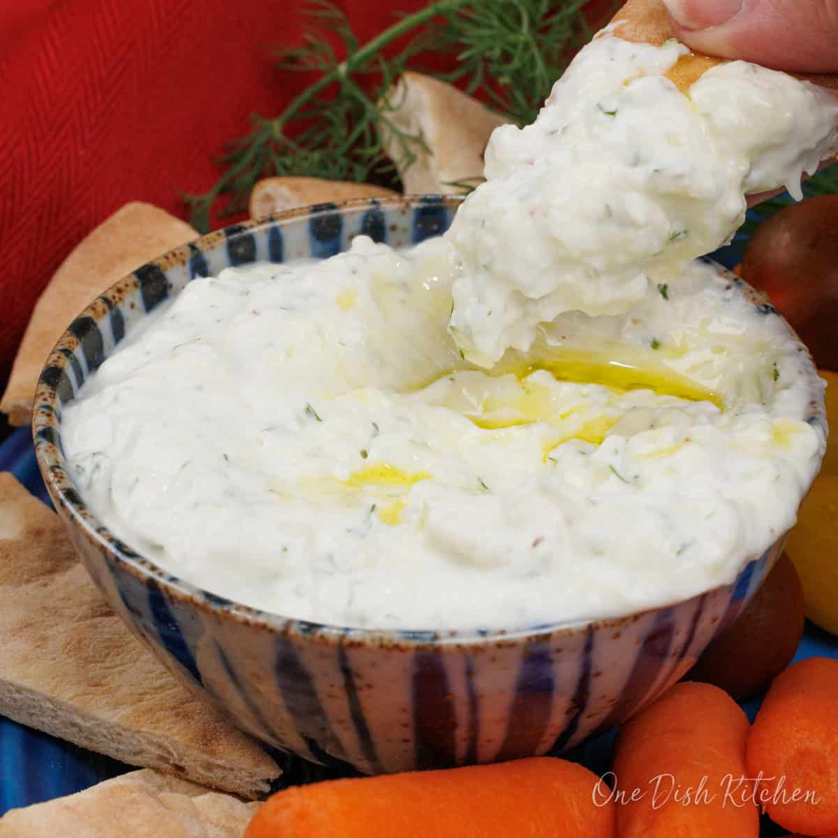 a small batch of tzatziki sauce in a blue bowl with chips on the side.