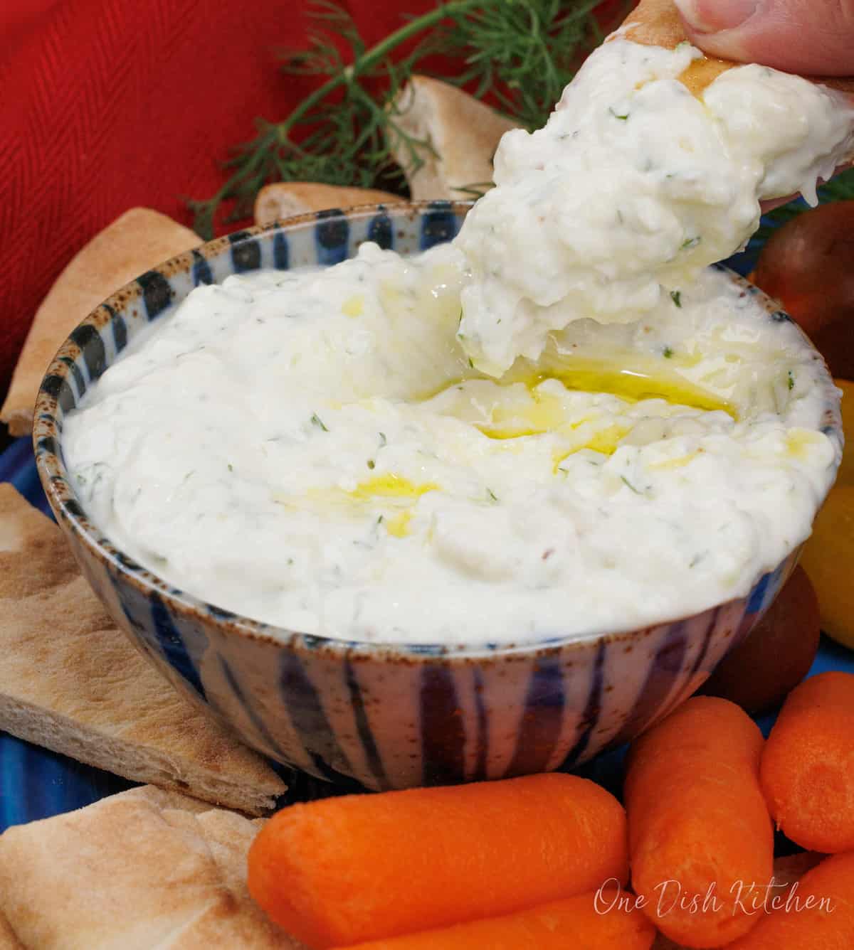 a small bowl of tzatziki with a pita chip on the side of the bowl