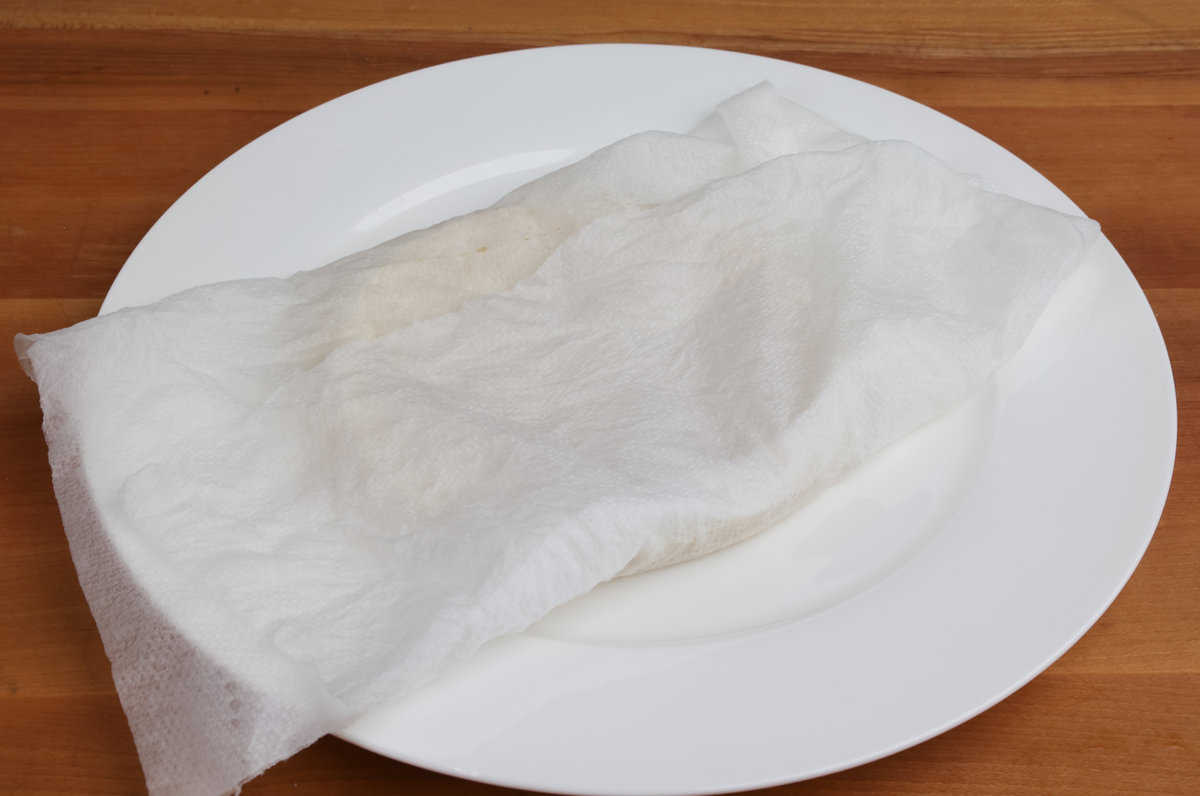 tortillas wrapped in a wet paper towel on a white plate