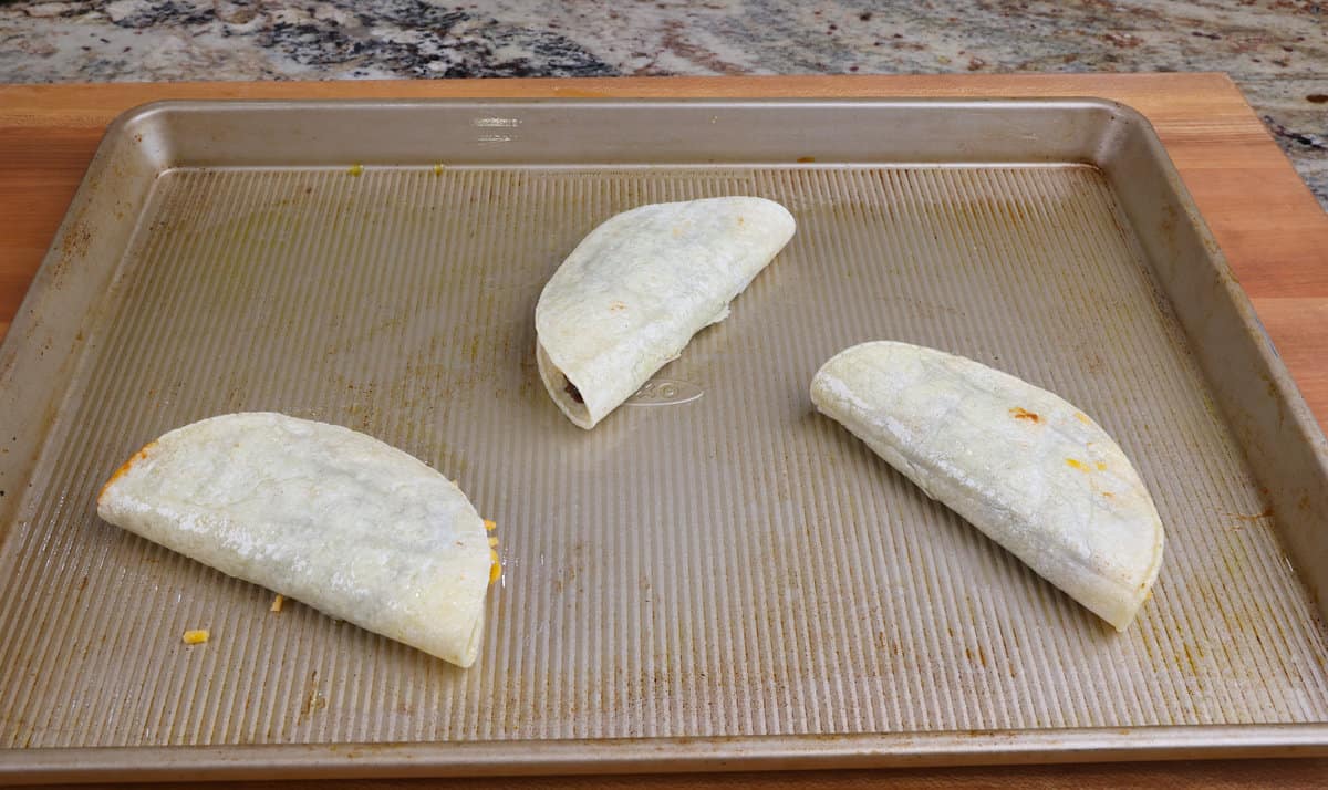 three unbaked black bean tacos on a baking sheet