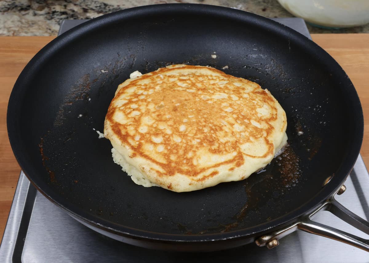 one pancake cooking in a non stick skillet