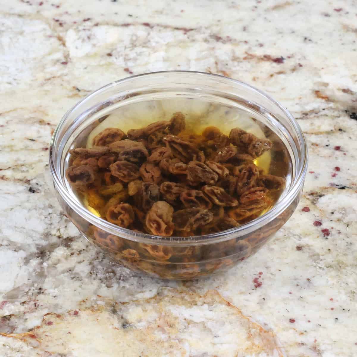 raisins soaking in hot water on a kitchen counter.