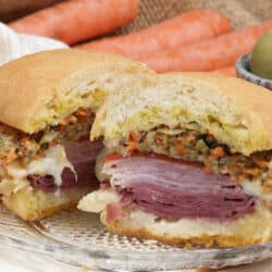 a muffuletta for one cut in half on a white plate with Authentic New Orleans Recipe text on bottom