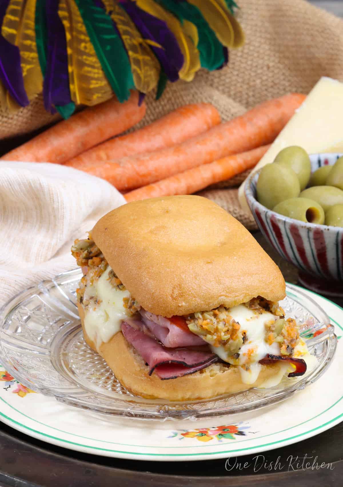 a heated mini muffuletta next to a mardi gras mask.