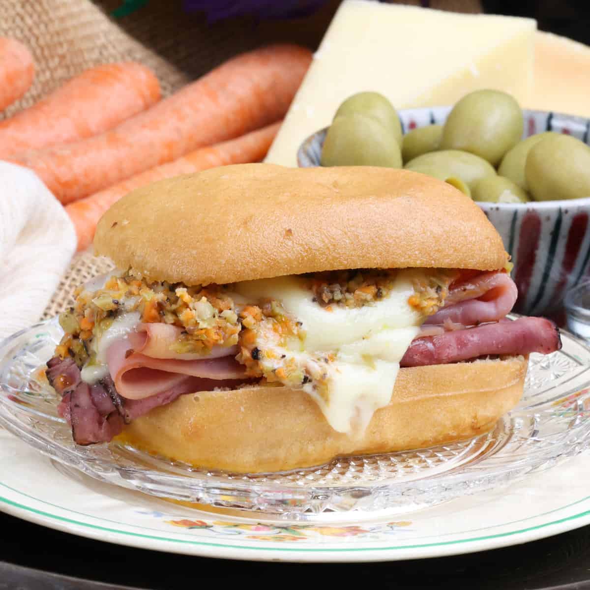 a single muffuletta sandwich with cheese melted and dripping down the sides.