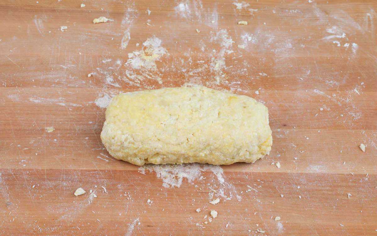 a ball of gnocchi dough on a wooden cutting board.