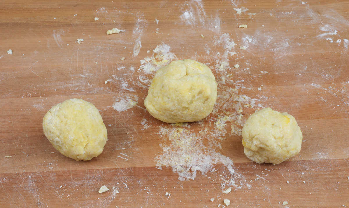 3 balls of gnocchi dough on a cutting board.