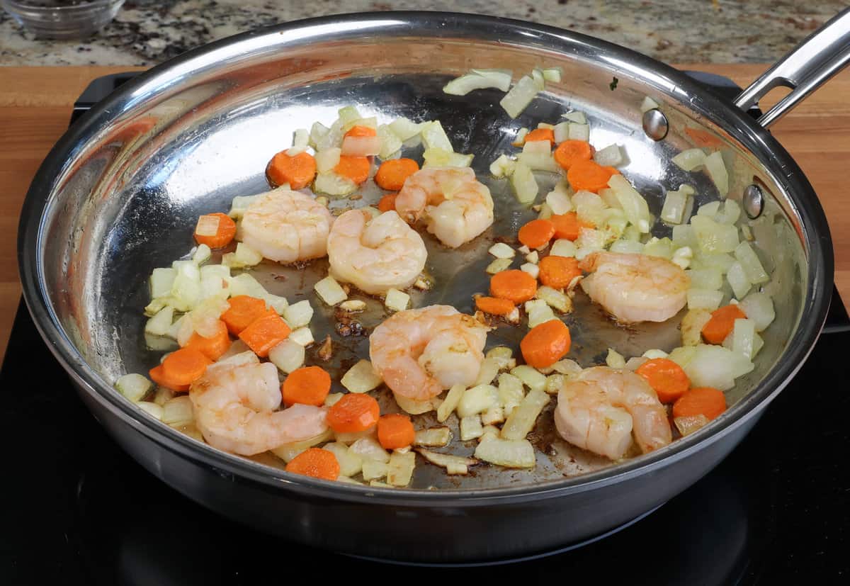 shrimp cooking with vegetables in a skillet.