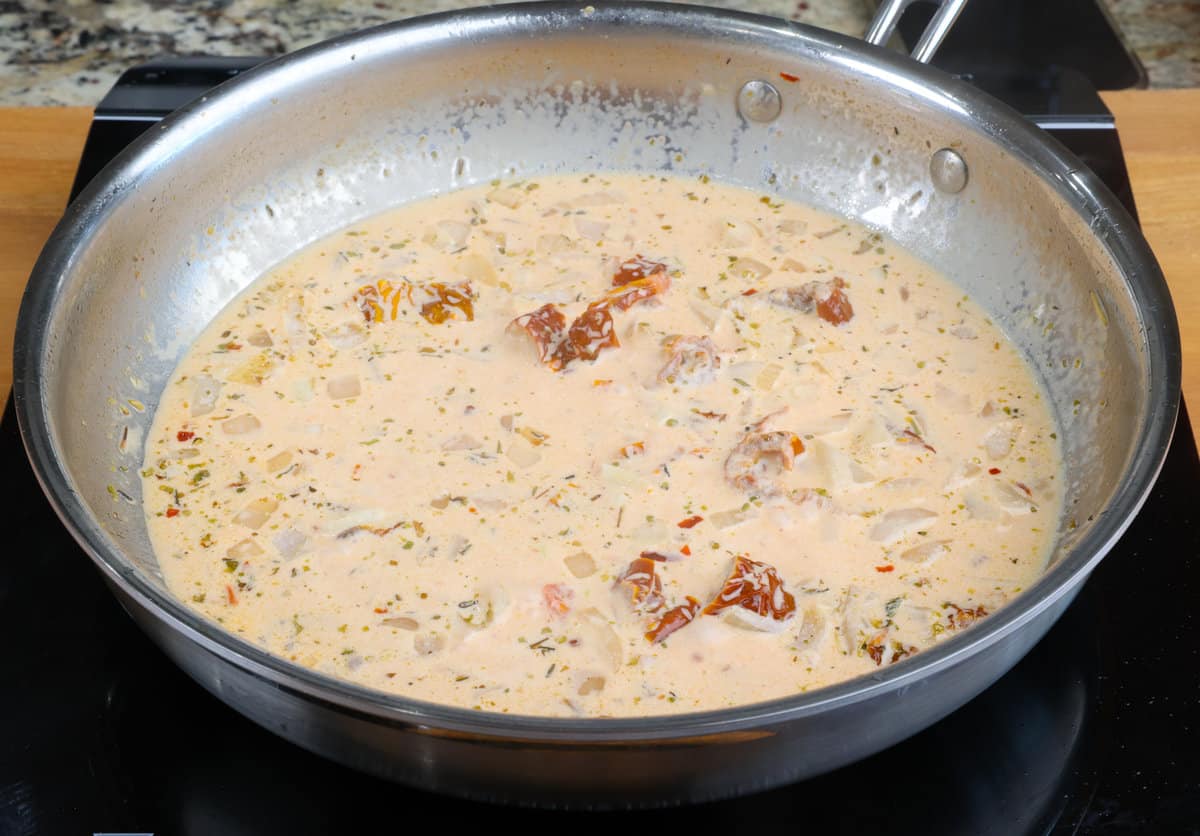 a cream sauce in a skillet simmering on the stove