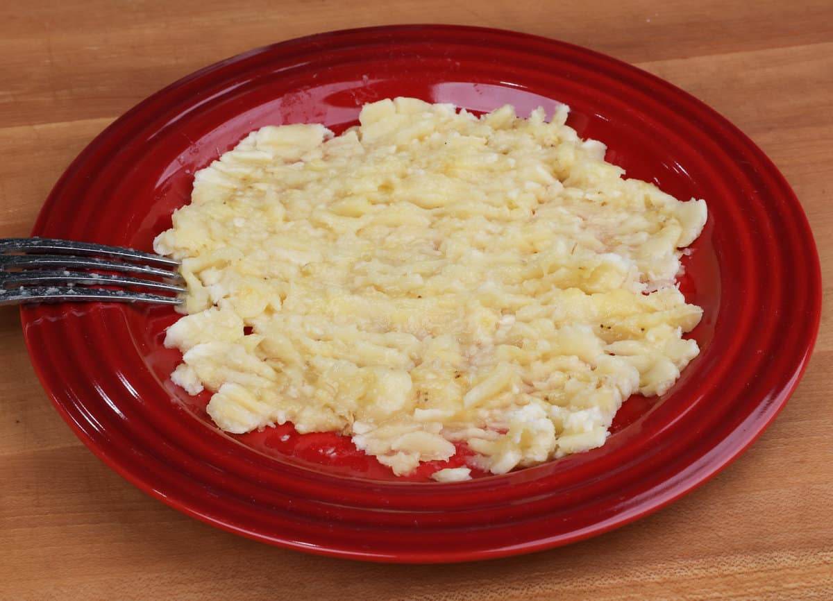 one mashed banana on a red plate.