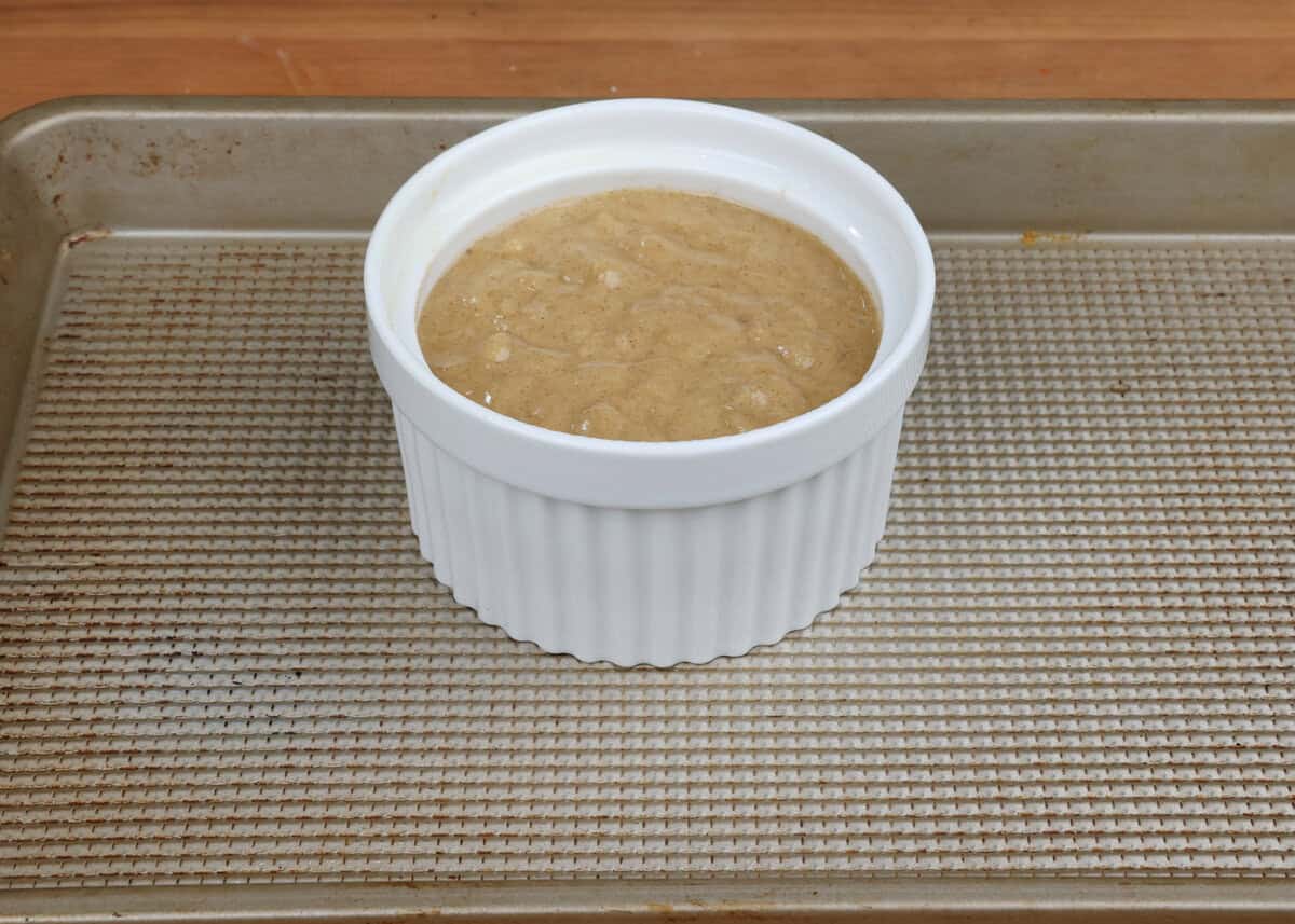 unbaked banana nut bread in a small ramekin on a baking sheet.