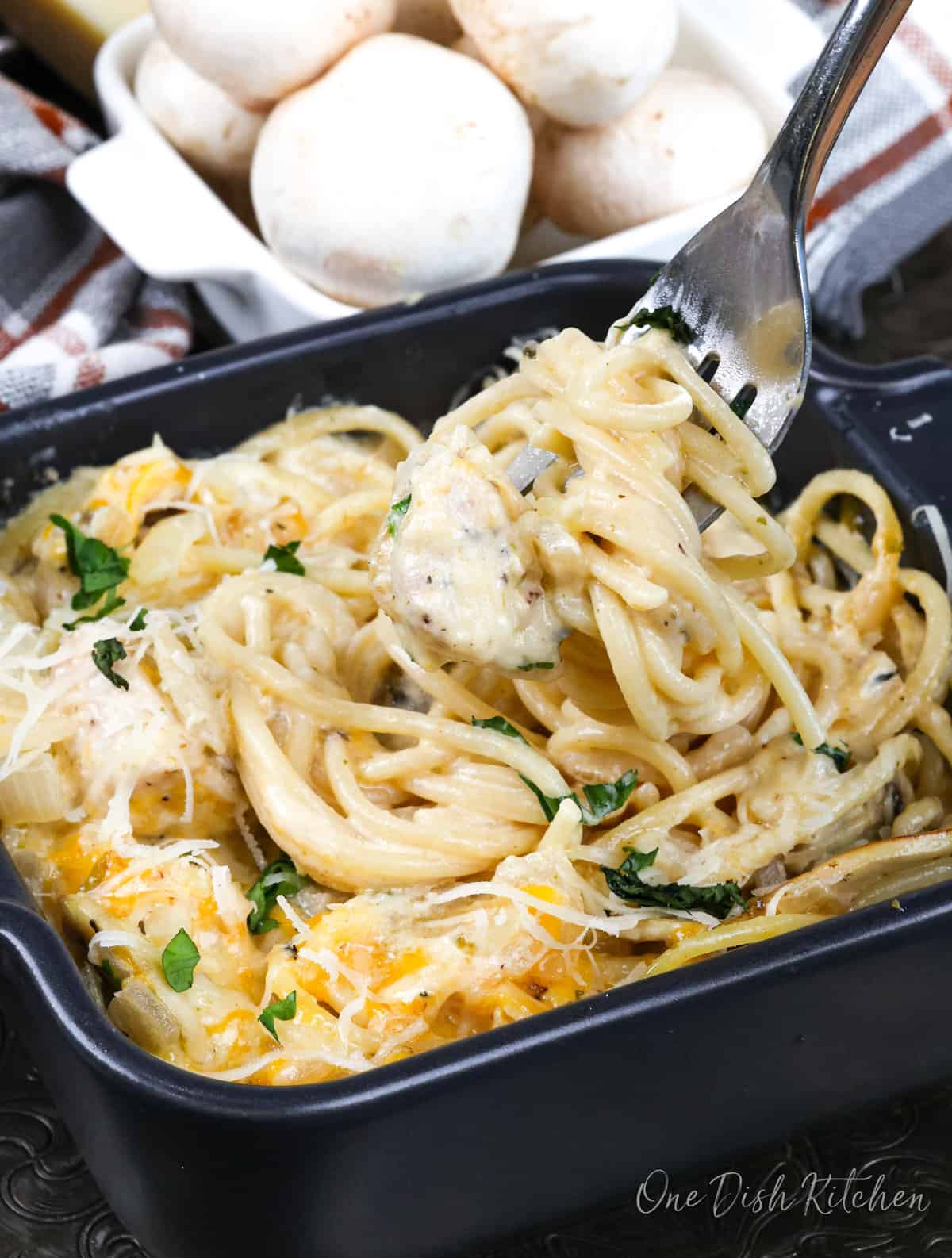 chicken tetrazzini in a small. baking dish next to a bowl of fresh whole mushrooms.