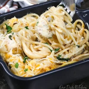 a small chicken tetrazzini with a fork on the side of the dish.