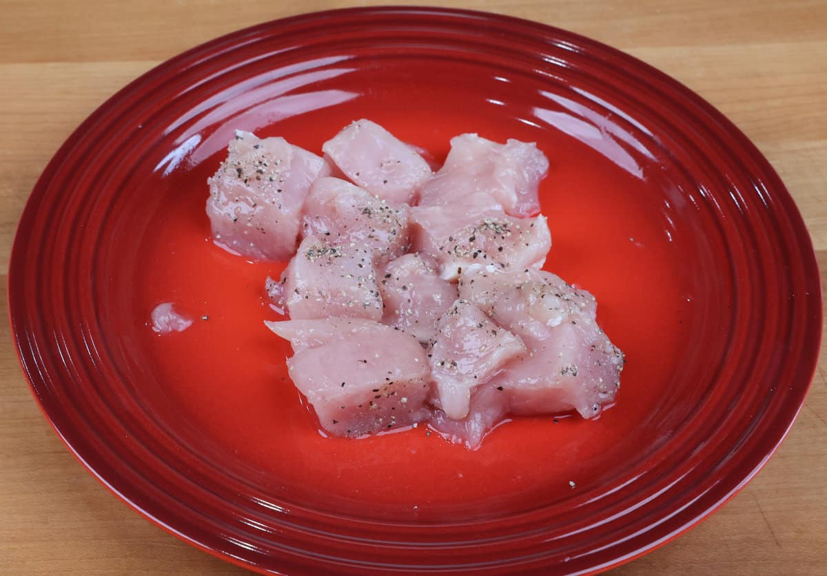 pieces of raw chicken on a red plate