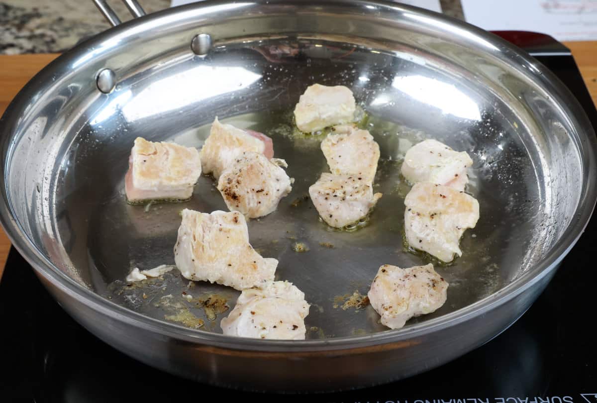 chicken pieces cooking in a skillet