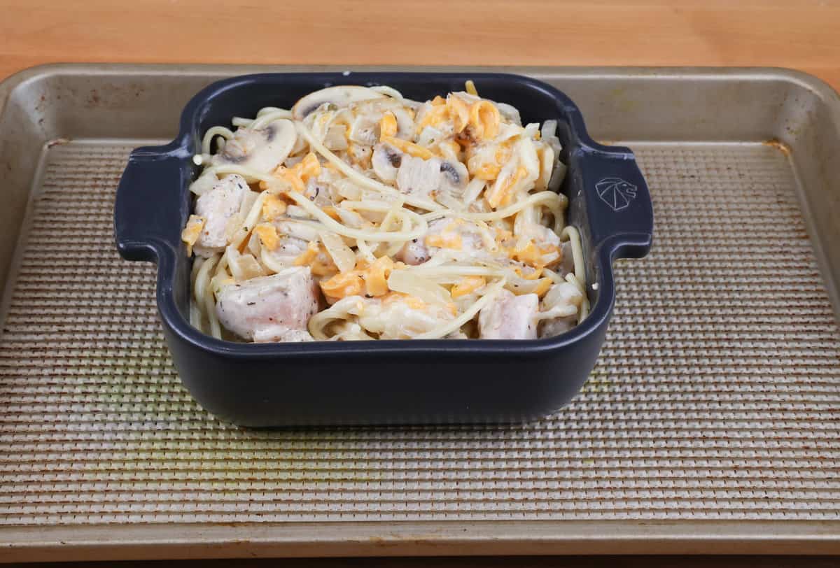 chicken tetrazzini in a small baking dish on a rimmed baking sheet