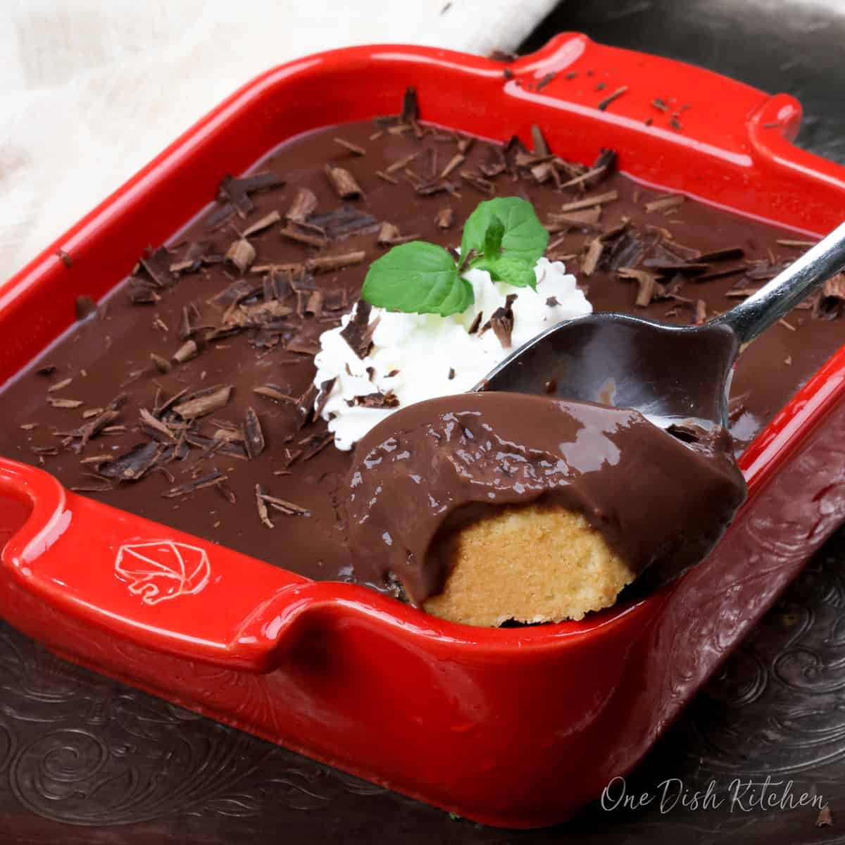 a small chocolate cream pie with a spoon scooping out some of the crust with pudding on the side.