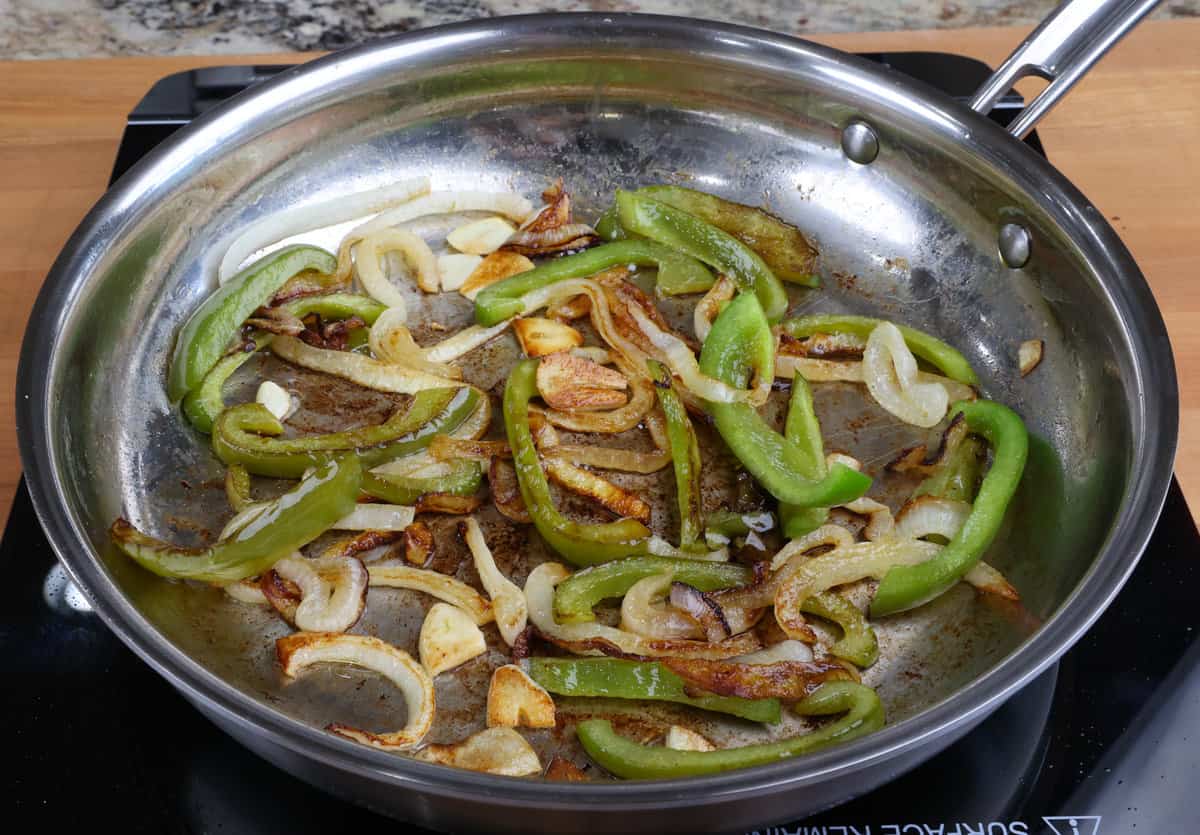 sliced green bell peppers, onions, and garlic in a skillet.