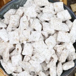 an overhead view of a bowl of muddy buddies made with white chocolate chips on a silver tray