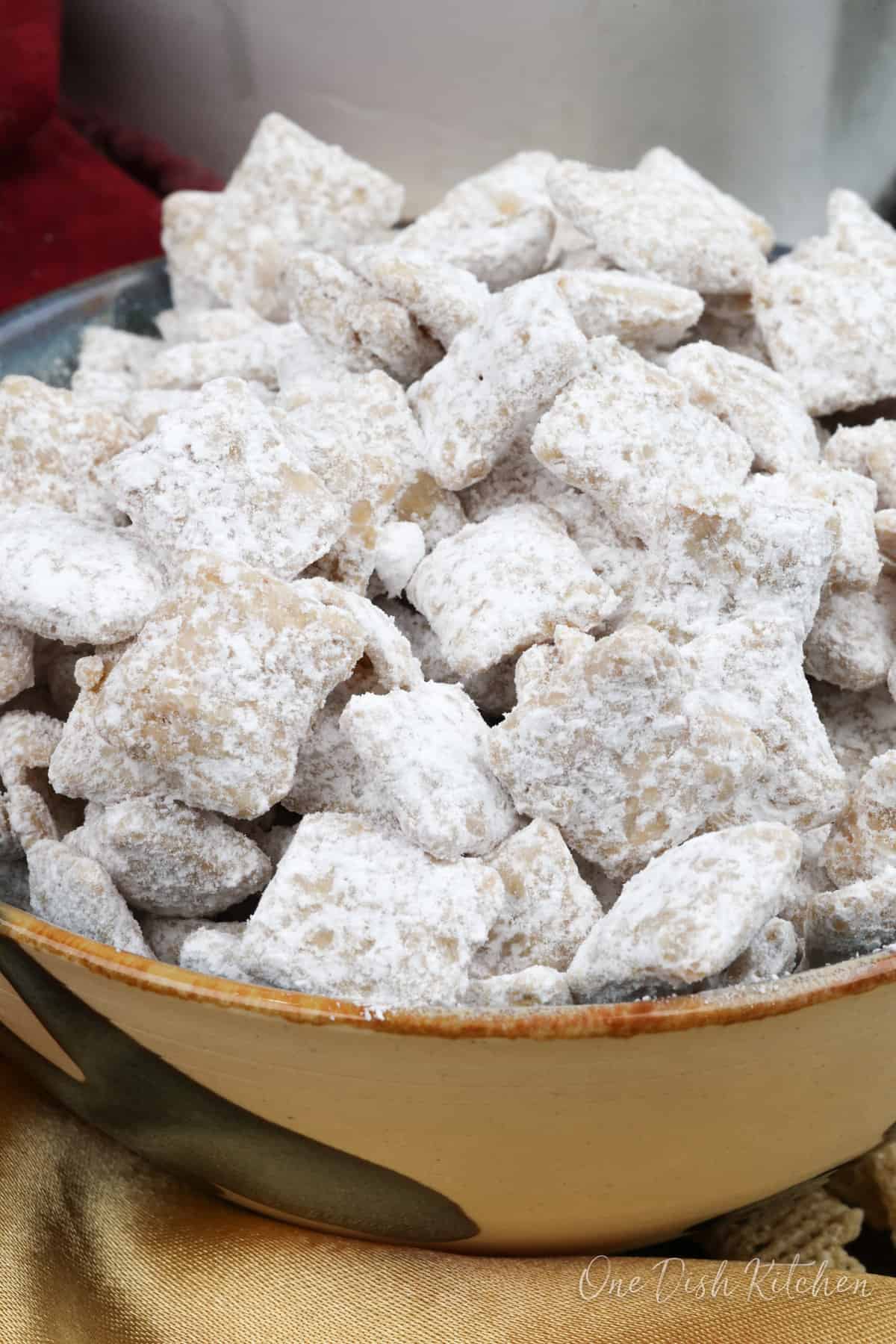 a bowl of puppy chow next to a gold napkin