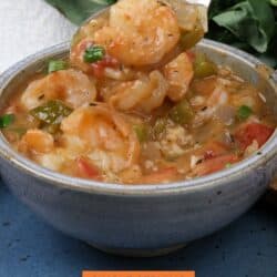 a blue bowl filled with shrimp etouffee with a spoon on the side.