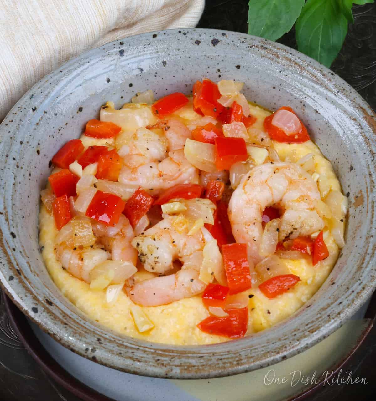 an overhead view of shrimp, onions, garlic and red peppers on top of cheese grits