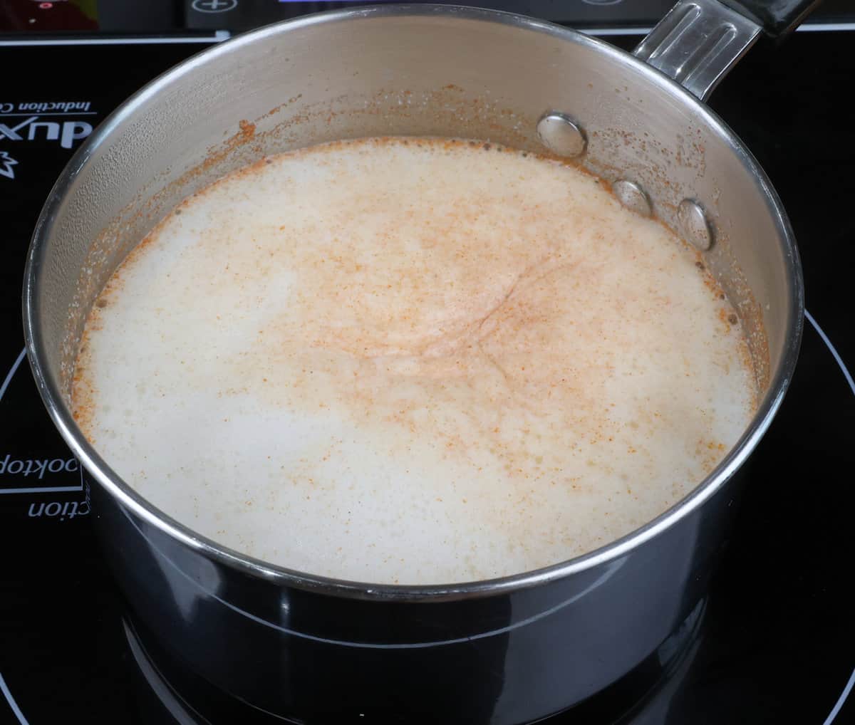 milk, paprika, and garlic powder simmering in a small pot
