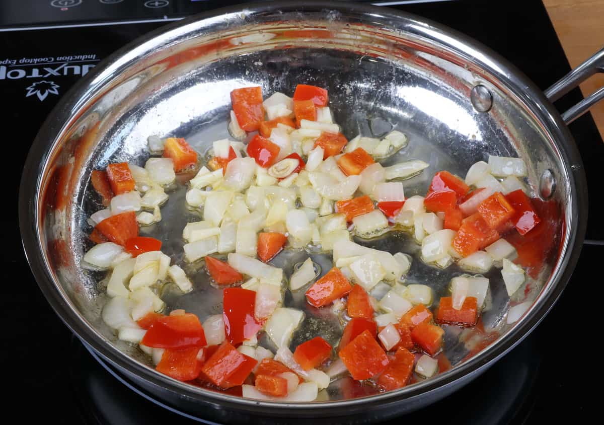 chopped onions, red bell peppers, and garlic cooking in a skillet