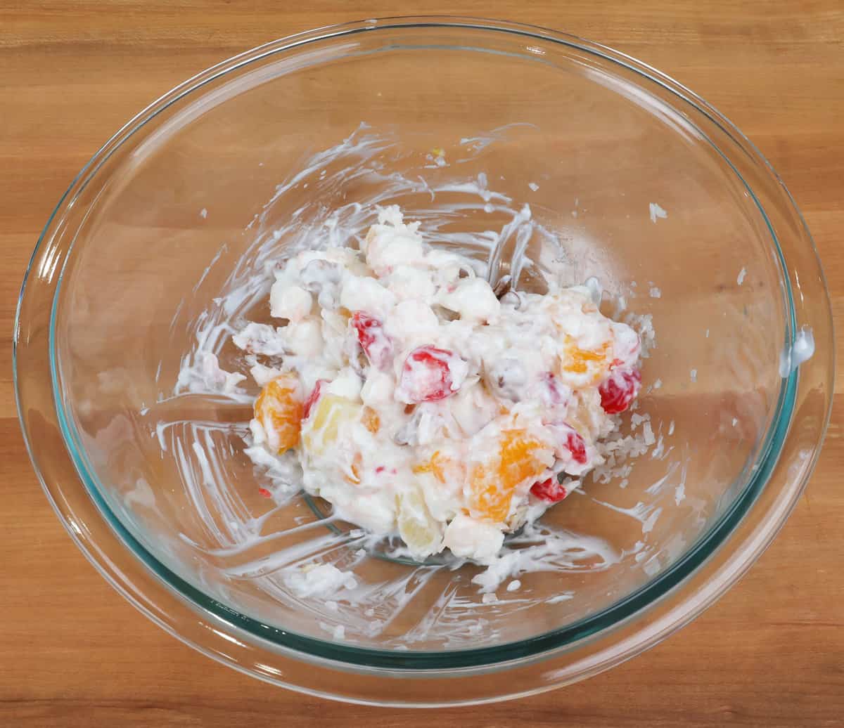 an ambrosia salad in a mixing bowl on a kitchen counter.