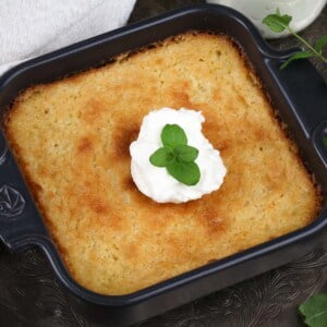 a mini buttermilk pie in a small black baking dish topped with whipped cream and fresh mint