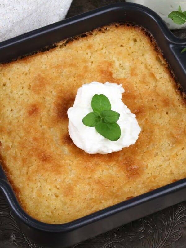 a mini buttermilk pie in a small black baking dish topped with whipped cream and fresh mint