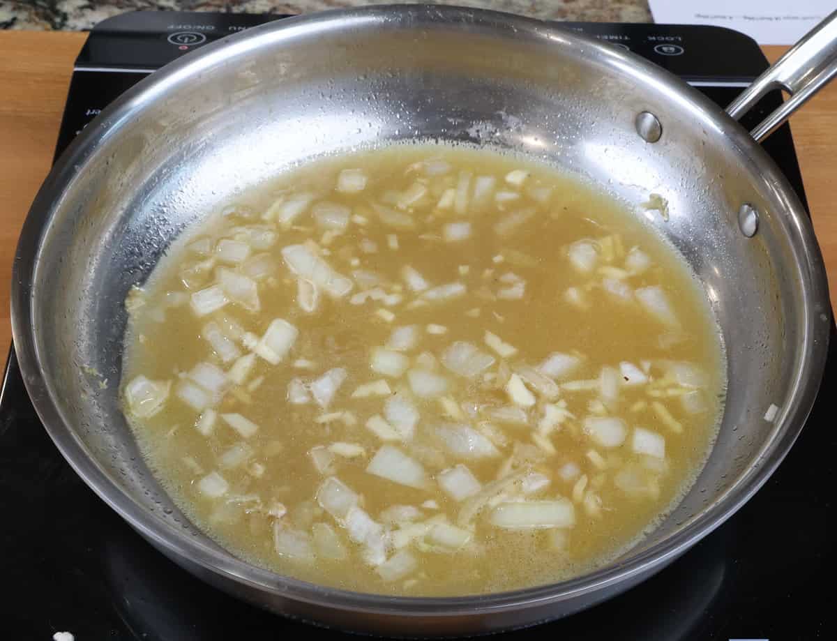 chicken broth simmering in a pan on the stove.